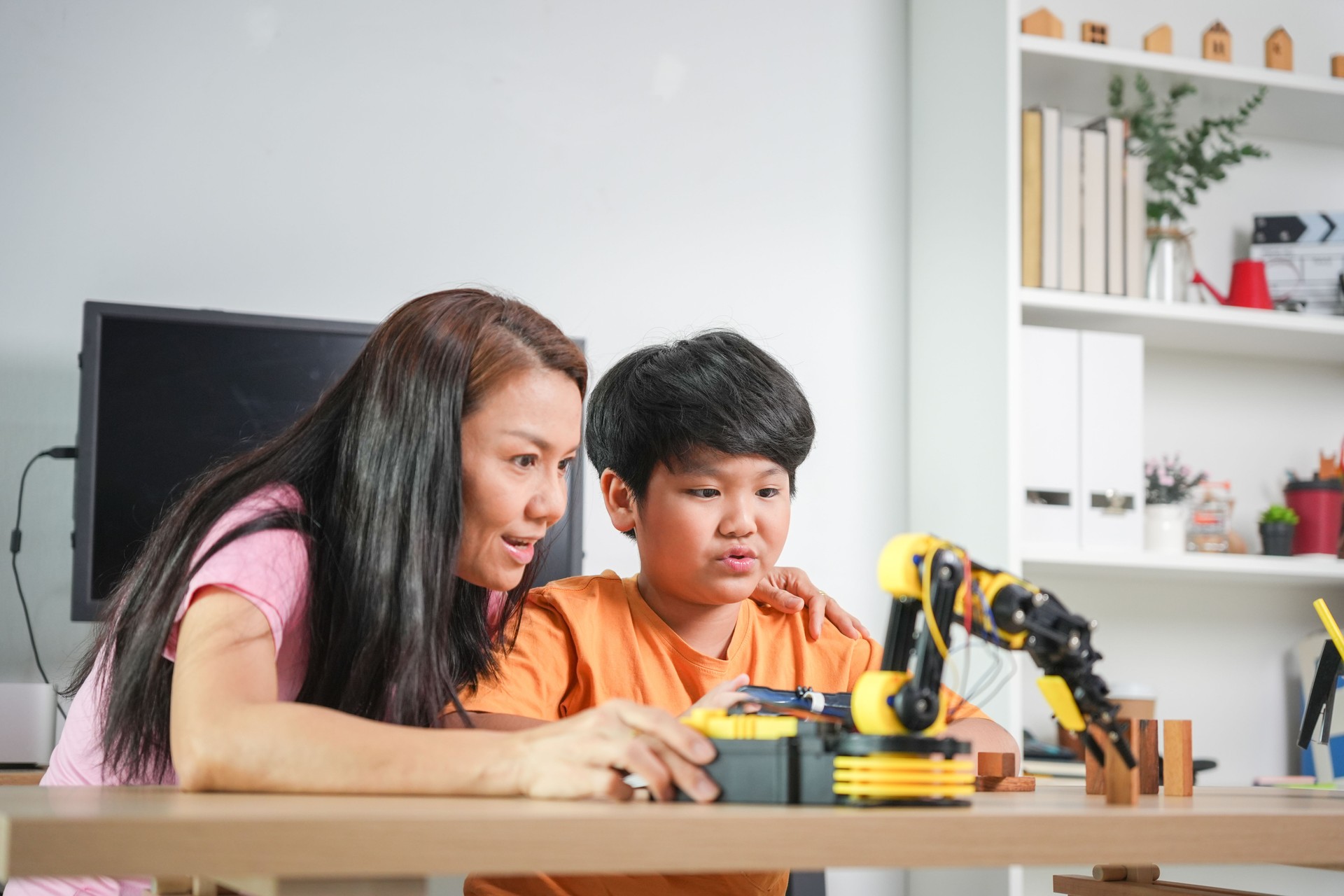 Young Boy Engaged in STEM Education with Robot Arm, Parent and Child Explore Technology with Robotic Kit, Mother and Son Learning Robotics Together