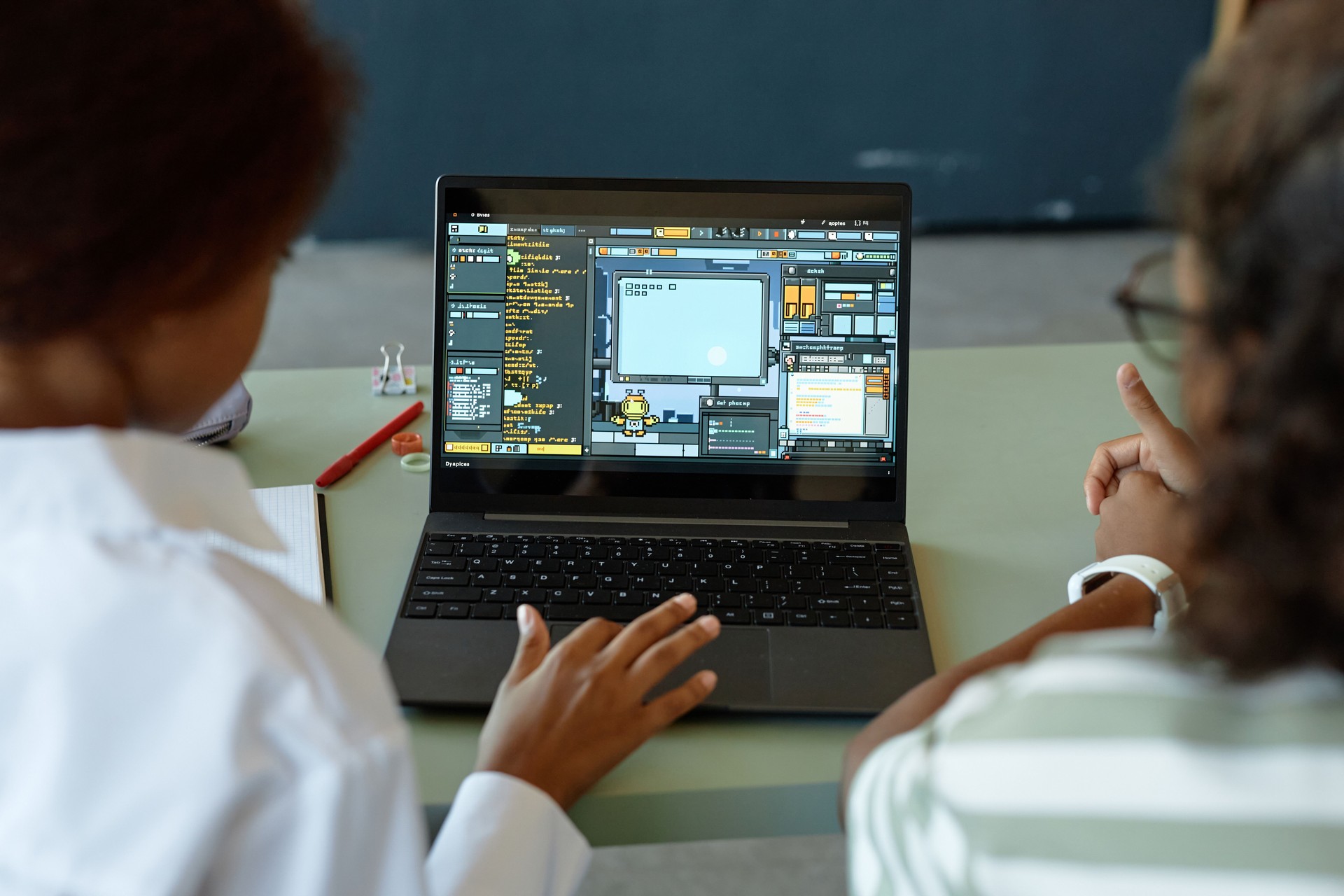 Over Shoulder of Two Kids Using Laptop in Class with Playful IT Lesson on Screen