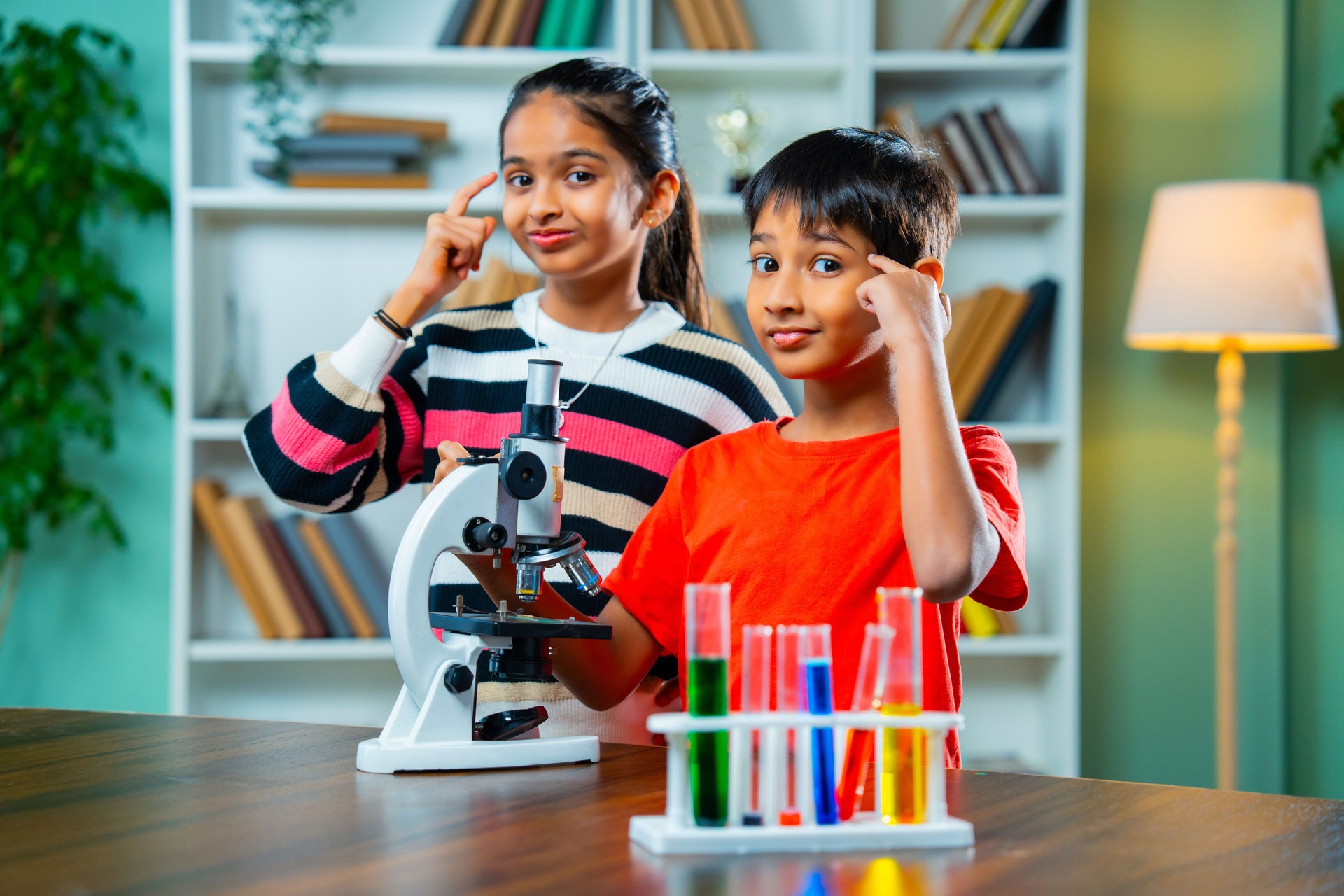 Curious Indian kids using a microscope and test tubes in a playful science experiment at school